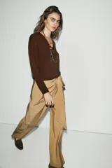 Pantalón de tiro bajo con diseño cruzado tipo pareo en el frente y lazo ajustable. Presenta pernera recta y cierre lateral con cremallera oculta.