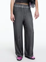 Pantalón de corte amplio y relajado, confeccionado en viscosa con efecto de teñido en frío y acabado lavado. Presenta cintura elástica y detalles de desgaste en costuras y ruedo.