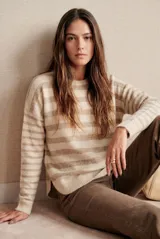 Sweater de punto con diseño de rayas horizontales en tonos beige y arena, cuello redondo, manga larga y corte holgado con aberturas laterales en el ruedo.