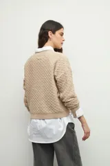 Sweater de punto con textura en relieve, cuello redondo y mangas largas con puños ajustados.