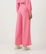 Pantalón tipo pantalona de tiro alto y corte amplio, confeccionado en tejido de ribana texturizada color rosado. Cuenta con cintura elástica y lazo ajustable con detalle de abalorios en los extremos.