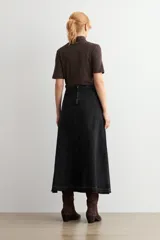 Falda larga de jean color negro, con diseño de paneles verticales y ruedo deshilachado.