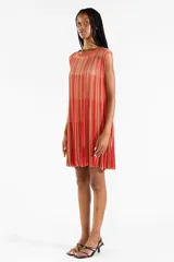 Vestido corto sin mangas confeccionado en tejido de punto, con cuello redondo, corte suelto y diseño a rayas verticales en tonos rojos, naranjas y dorados.