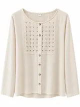 Camisa de manga larga color manteca, con cuello redondo y cierre frontal de botones. Presenta un panel frontal de broderie con diseño geométrico perforado.