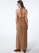 Vestido largo color marrón claro, con cuello halter y espalda descubierta.