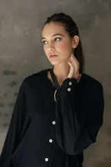 Camisa de corte relajado y caída fluida, con cuello clásico, mangas largas con puños anchos y cierre frontal con botones a contraste.