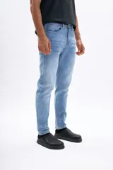 Pantalón de jean celeste de corte slim, con efecto lavado, bolsillos clásicos y cierre frontal de botón y cremallera.
