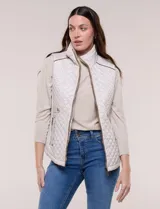 Chaleco acolchado de diseño entallado color beige, con matelaseado en patrón de rombos en frente y espalda, cuello alto estructurado y cierre frontal completo con cremallera metálica y ribete a contraste.