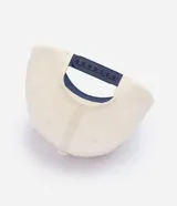 Gorra de béisbol con diseño bicolor, cuerpo en color crema y visera en azul marino. Presenta un bordado frontal con lettering en relieve color azul.