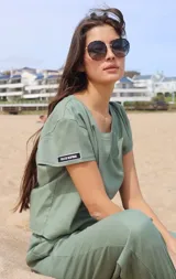 Remera de corte holgado y cuello redondo, confeccionada en una mezcla de lino y elastano. Presenta mangas cortas con una etiqueta decorativa rectangular en la manga derecha con la frase 'FELIZ DE RESPIRAR'.