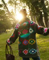 Saco tejido a mano de color negro, con diseño geométrico multicolor, cuello smoking y cierre frontal con dos botones.