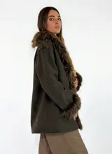 Chaqueta midi color crudo con detalles de piel sintética en el cuello y los puños. Presenta un diseño abierto con bolsillos laterales y una textura suave.