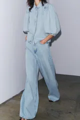 Camisa de denim celeste con cuello solapa, manga corta abullonada y cierre frontal con botones.