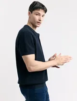 Remera color café de tejido de punto, con cuello polo y mangas cortas.