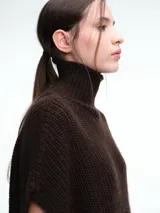 Chaleco tipo poncho de tejido de punto color tostado, con cuello polera y diseño holgado con laterales abiertos.