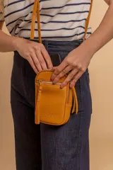 Bandolera compacta color rosado, con correa regulable y desmontable. Tiene apertura superior, bolsillo frontal con cierre y detalle de borla, y bolsillo trasero sin cierre. El interior está forrado en tela y cuenta con un bolsillo adicional.