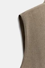 Top de punto fino color marrón topo, con cuello subido y diseño sin mangas.