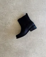 Bota de cuero negra, desmontable 3 en 1, con detalle de arnés con aros metálicos y hebillas.