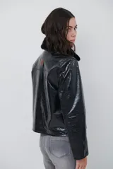Chaqueta de efecto cuero brillante con acabado charol, cuello con solapas de piel sintética, cierre frontal con botones y bolsillos laterales.