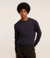 Suéter de punto color borgoña, con cuello redondo, sisas ligeramente desplazadas y bajo y puños acanalados.