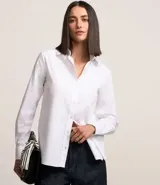Camisa básica de mujer confeccionada en tricolina de algodón, con cuello solapa, cierre frontal de botones y mangas largas con puños abotonados.