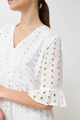 Vestido largo negro con tejido calado tipo broderie inglés, escote en V, mangas cortas con volado y diseño de capas con volados en el ruedo.