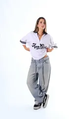 Chomba blanca de pique con cuello y solapa negros, cierre frontal parcial y mangas cortas con ribetes negros. Estampado frontal en cursiva negra.