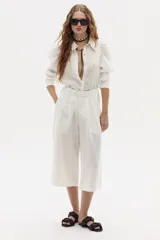 Camisa blanca de lino con cuello clásico, mangas largas abullonadas y cierre frontal con botones.