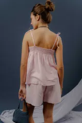Conjunto de dos piezas confeccionado en lino color rosado, compuesto por una musculosa de corte amplio con breteles de lazo regulables y un short con elástico en la cintura y bolsillos delanteros redondeados.