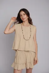 Blusa color beige con alforzas en la parte delantera y trasera, cuello redondo y mangas cortas con bordados artesanales.
