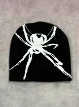 Gorro tipo beanie de punto color negro con diseño de araña en color blanco en la parte frontal.