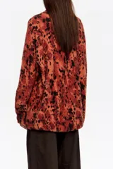 Jersey de pelo con cuello alto, manga larga y diseño holgado. Presenta un estampado animal print difuminado en tonos rojizos y negros.
