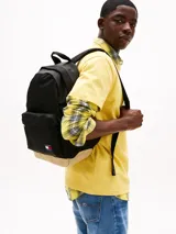 Mochila Tommy Jeans Essential negra con base color beige. Tiene un compartimento principal con bolsillo interior de malla, un bolsillo exterior con cremallera, asa superior y correas ajustables y acolchadas.