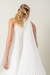 Vestido largo blanco de gasa plisada, sin mangas y con cuello halter bordado con perlas.