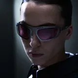 Lentes de sol de diseño envolvente con montura de acero inoxidable en color gunmetal y lentes de nylon color violeta. Presentan un diseño deportivo con detalles perforados en la parte superior del marco y patillas de acetato.