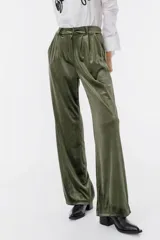 Pantalón de terciopelo verde militar, de corte palazzo, con cintura alta y cinturón con hebilla forrada. Presenta pinzas en la cintura y bolsillos laterales.