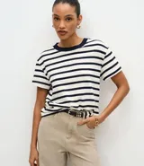 Remera de corte boxy confeccionada en algodón, con diseño de rayas horizontales en blanco y azul marino. Presenta cuello redondo de punto en color contrastante y mangas cortas.