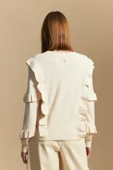 Sweater negro de manga larga, tejido suave y caída liviana, con volados en el delantero y mangas. Silueta recta.