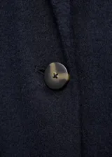 Abrigo largo de corte recto confeccionado en mezcla de lana, con cuello de solapa, cierre frontal de dos botones y dos bolsillos laterales con solapa.