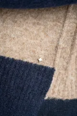 Sweater de tejido de punto con diseño color block. Cuerpo principal en beige jaspeado, mangas y puños en azul marino, y detalles en marrón en el cuello y puños.