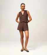 Short sastre de cintura alta, color marrón, con bolsillos laterales y detalles de tachuelas metalizadas.