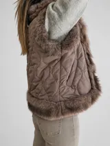 Chaleco acolchado color marrón con diseño matelassé y amplias solapas de piel sintética en tono chocolate. Presenta un corte recto y sin mangas, ideal para superposiciones.