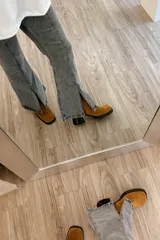 Pantalón jean gris de tiro medio alto, corte wide leg con tajo frontal.