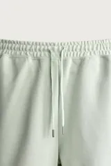 Bermuda estilo jogger de ajuste relajado, confeccionada en tejido interlock de algodón. Cuenta con cintura elástica ajustable con cordón, bolsillos frontales de vivo y diseño liso.