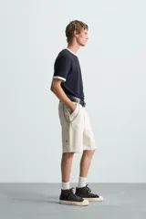 Bermuda relaxed fit confeccionada en tejido de algodón con efecto lavado. Presenta un diseño de cinco bolsillos, bolsillo multifunción en la pernera y tira lateral de estilo carpintero. Cuenta con cierre frontal con cremallera y botón.