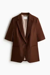 Blazer de manga corta de botonadura sencilla en color marrón, con solapas de muesca, cierre de un botón frontal, bolsillos delanteros ribeteados y forro interior.