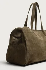Bolso de viaje de diseño minimalista confeccionado en piel con acabado serraje. Cuenta con compartimento principal con cierre de cremallera e imanes, interior con bolsillos organizadores y doble asa de mano en piel.
