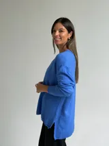 Sweater de tejido de punto color azul, con escote en V, manga larga con puños acanalados y diseño holgado con costura central vertical y ruedo asimétrico.