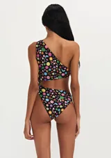 Traje de baño enterizo negro con estampado de símbolos y dibujos de colores. Diseño de un solo hombro con abertura en la cintura.
