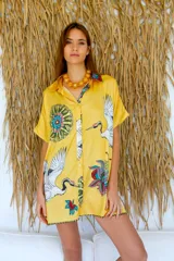 Camisola amarilla estampada con flores y grullas, de seda, con cuello camisero, mangas cortas y cierre frontal con botones.